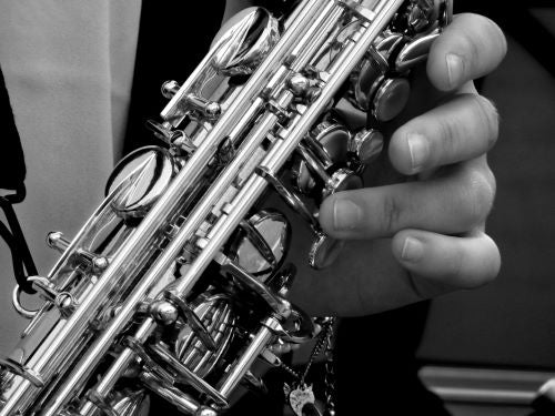 Plan rapproché d'une main faisant du saxophone en noir et blanc