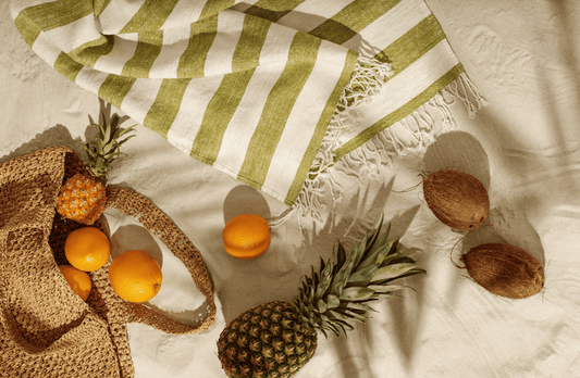 serviette de plage rayee sur le sable avec fruits autour