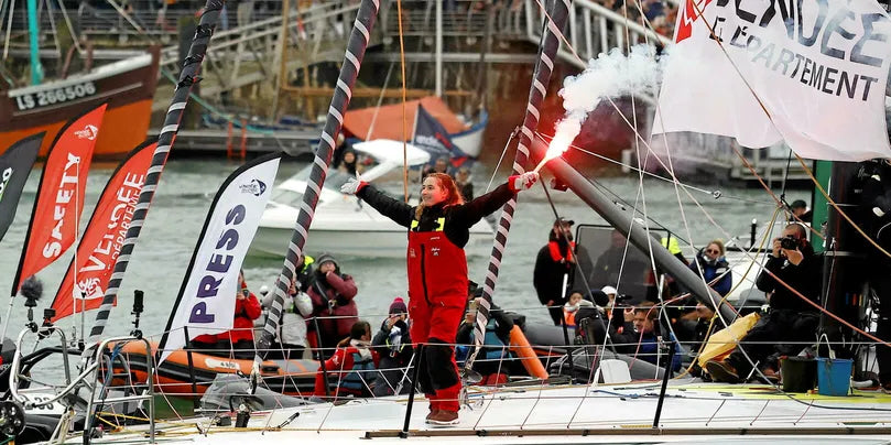 photographie arrivée de violette dorange sur son bateau avec des fumigènes rouges 