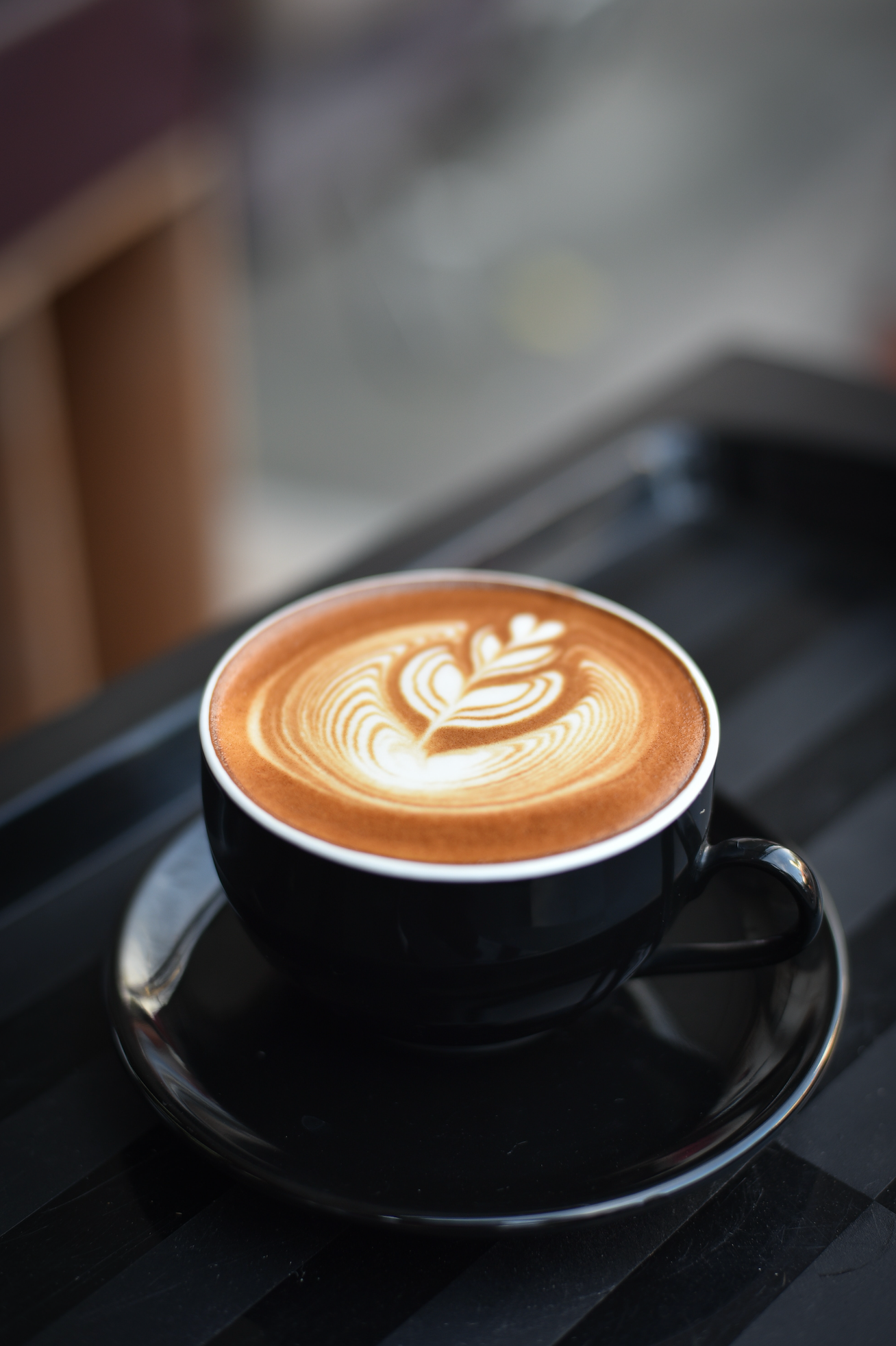 tasse noire à l'extérieur et blanche à l'intérieure, avec café au lait avec un coeur dessiné dedans