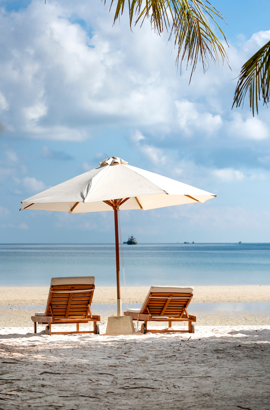 parasol beige sur place avec sable et mer à l'horizon avec deux assises en bois de part à d'autre sur parasol