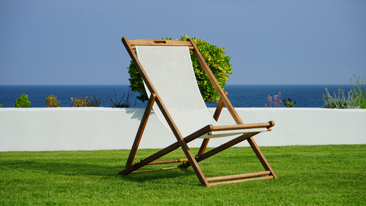 chaise pliable en bois avec tissu blanc confortable sur de l'herbe en bord de mer