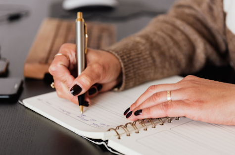 mains de femmes qui tiennent un stylo et qui écrivent sur un agenda
