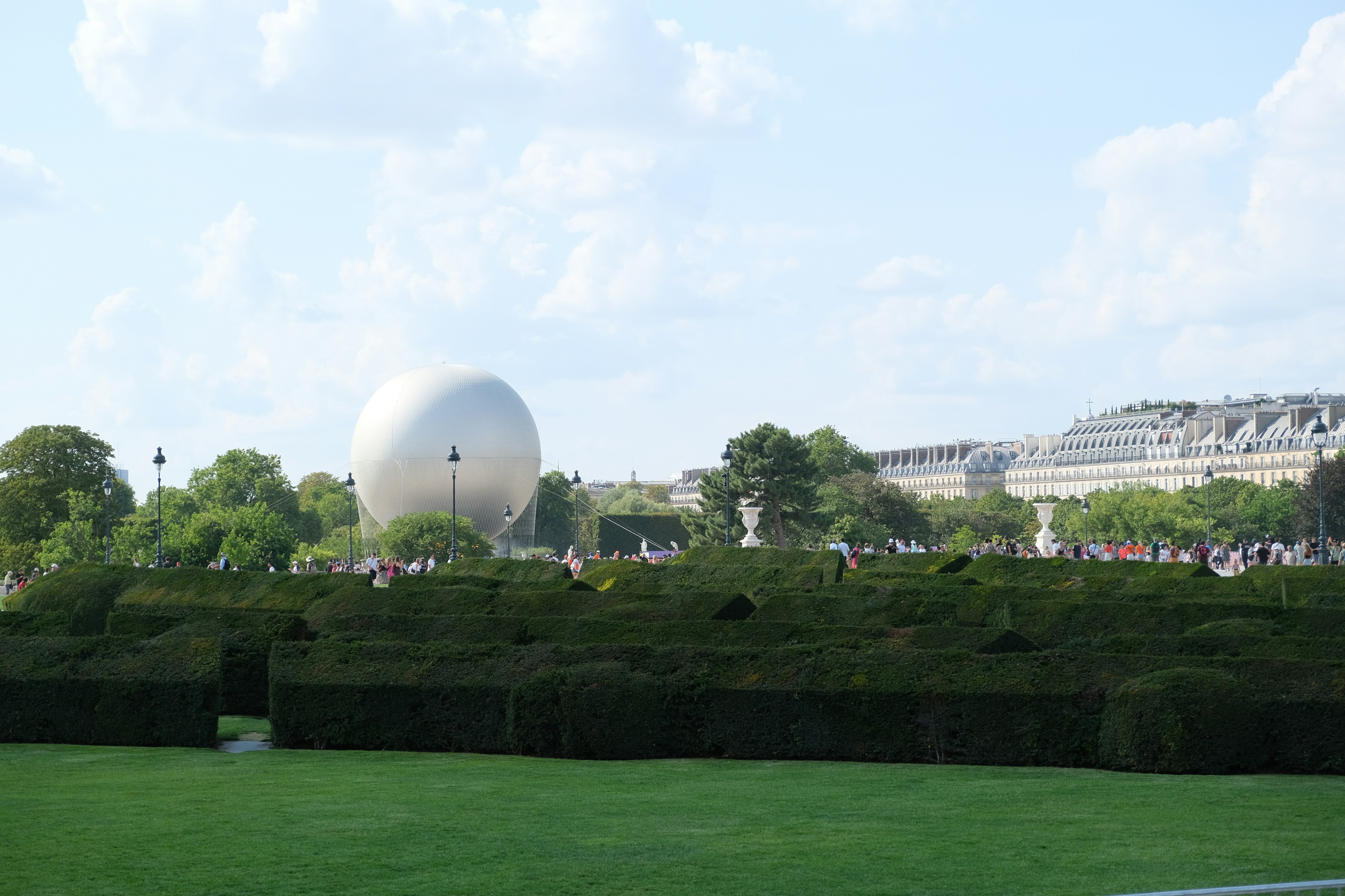 vasque olympique de loin, ciel bleu et il y a de l'herbe 