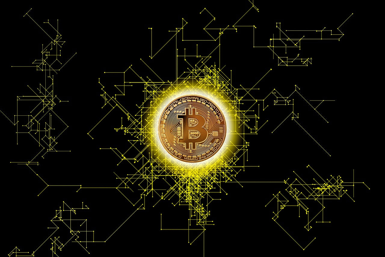 pièce de Bitcoin dorée avec le symbole "₿" au centre, entourée d'un halo lumineux jaune. Elle est placée sur un fond noir avec des lignes et des connexions jaunes, évoquant un réseau numérique ou une blockchain. 