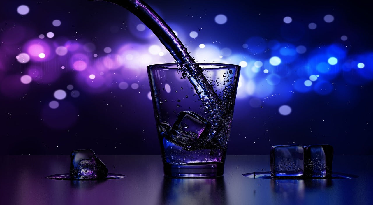eau qui est versée dans un verre avec glaçons sur un fond violet cosmos