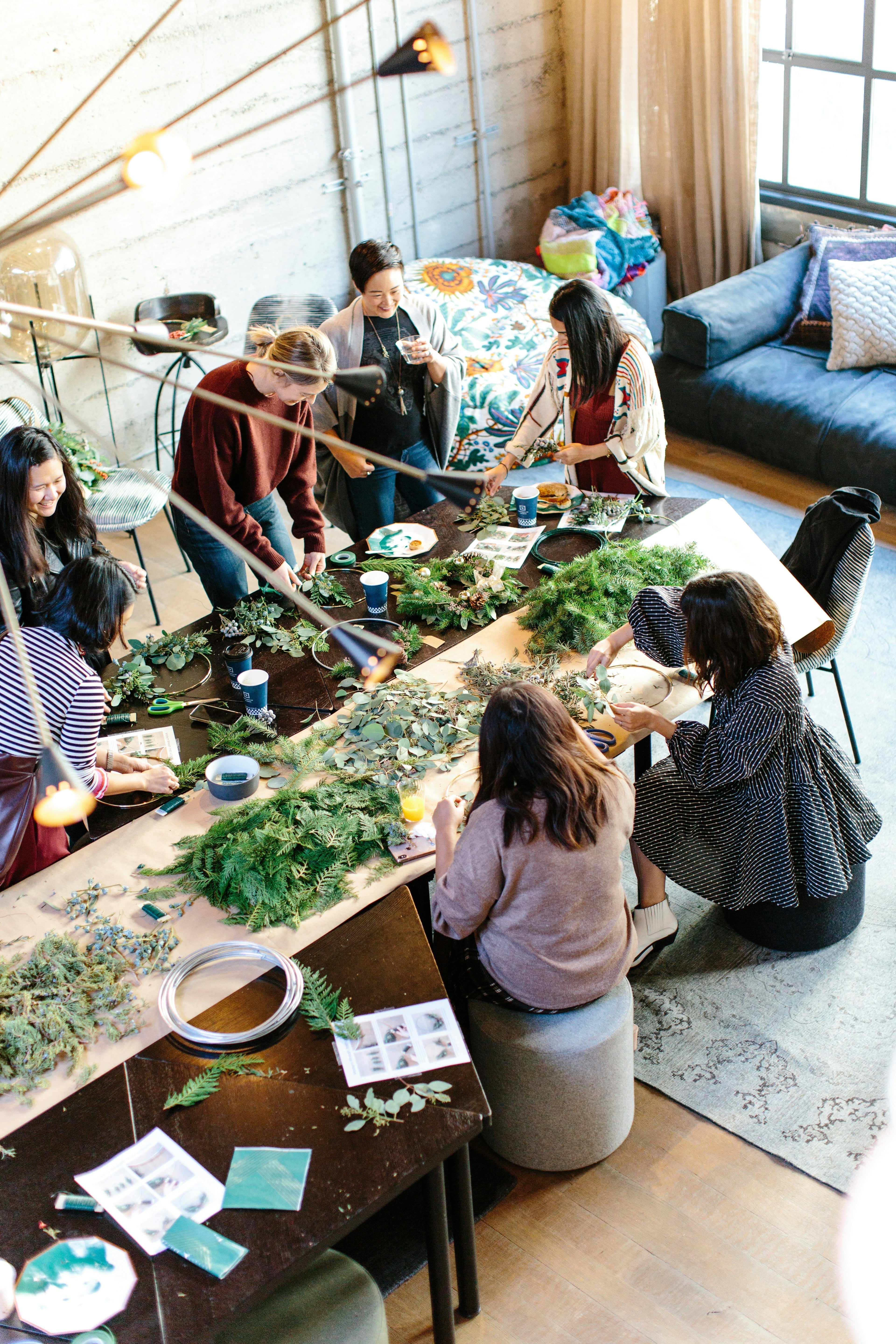 personnes dans un maison autour d'une table qui font un atelier avec du feuillage 