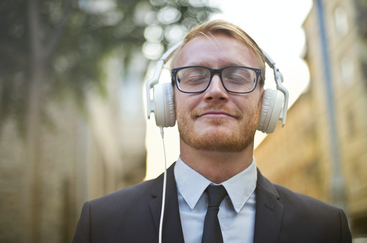 homme-qui-ecoute-du-contenu-dans-un-casque-filaire-audio-blanc-dans-une-ville-avec-arriere-plan-flou