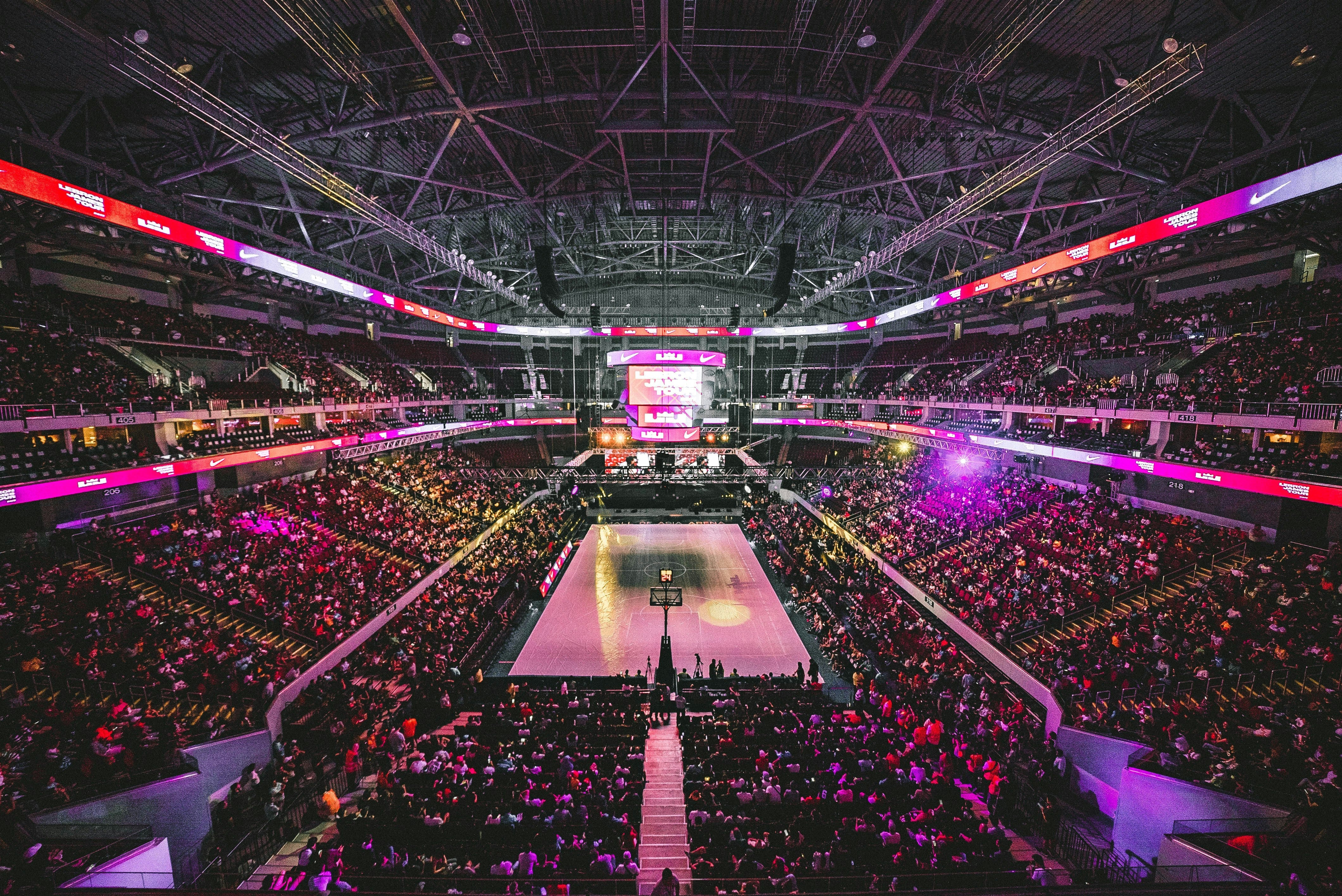 terrain de basket avec des leds violets et roses, pleins de foule de personnes 