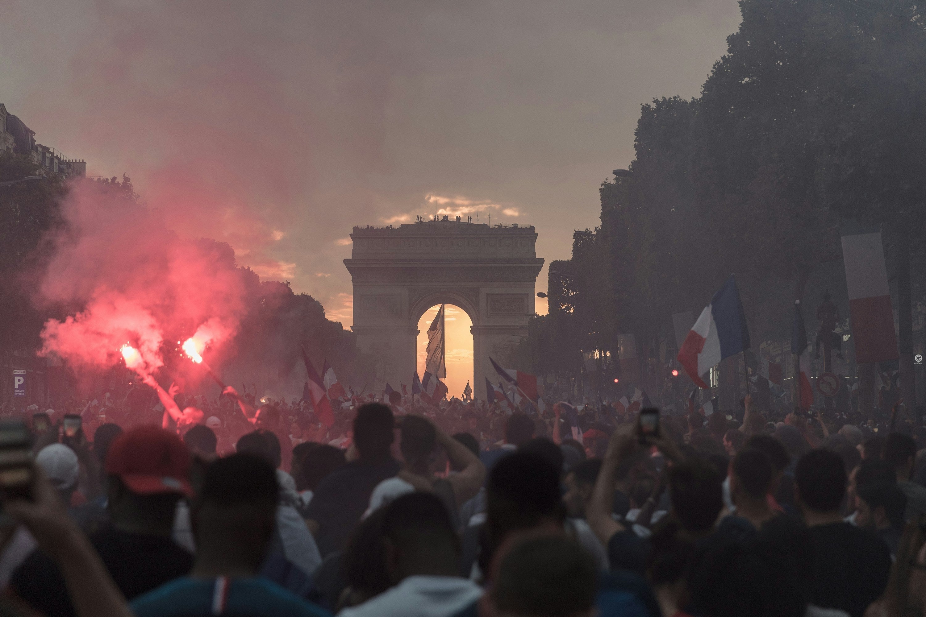 lors d'une finale de football, sur les champs Elysées. On voit l'arc de triomphe et une grosse foule avec des fumigènes et des drapeaux 