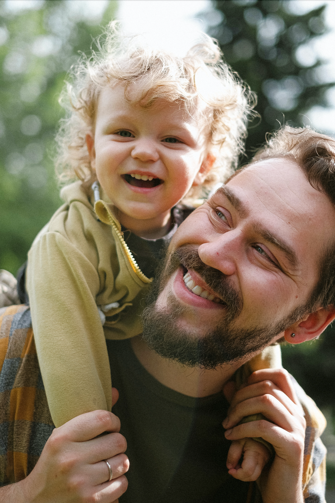 homme qui sourit avec son enfant sur ses épaules qui sourit également