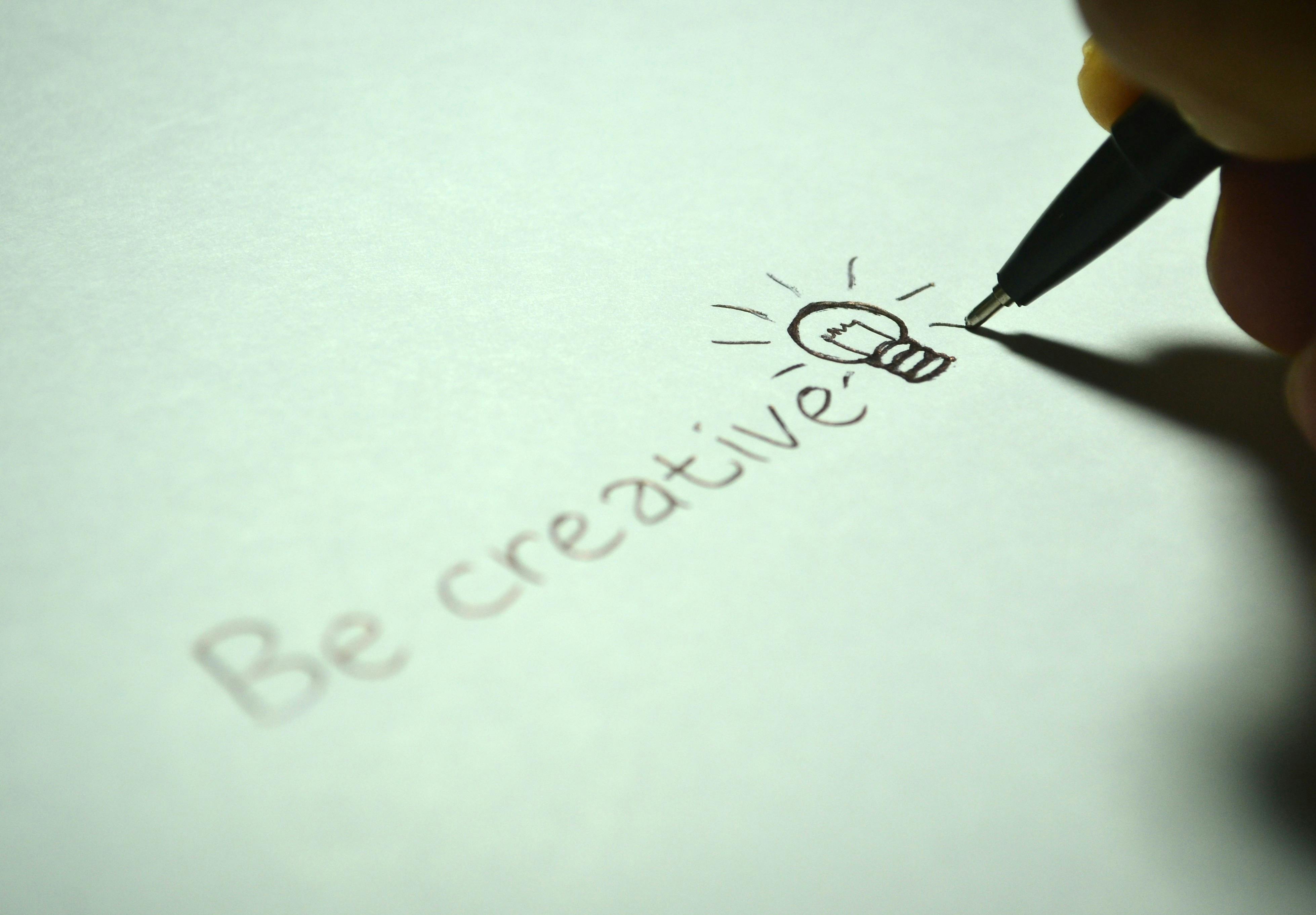 écrit au stylo sur une feuille "be creative" avec un dessin d'une lampe éclairée