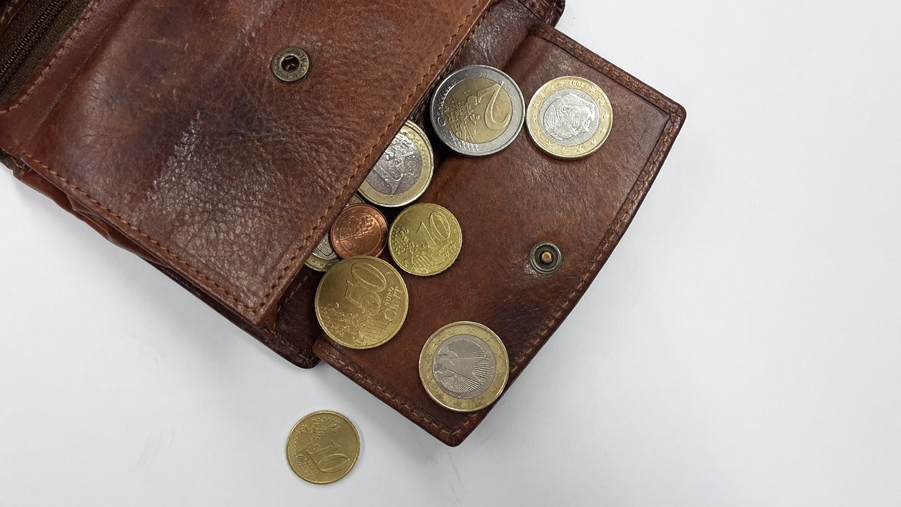Porte monnaie ouvert avec pièces de différentes valeurs qui en sortent