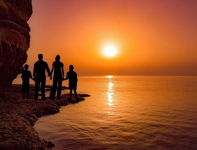 famille au bord de l'eau face à un couché de soleil