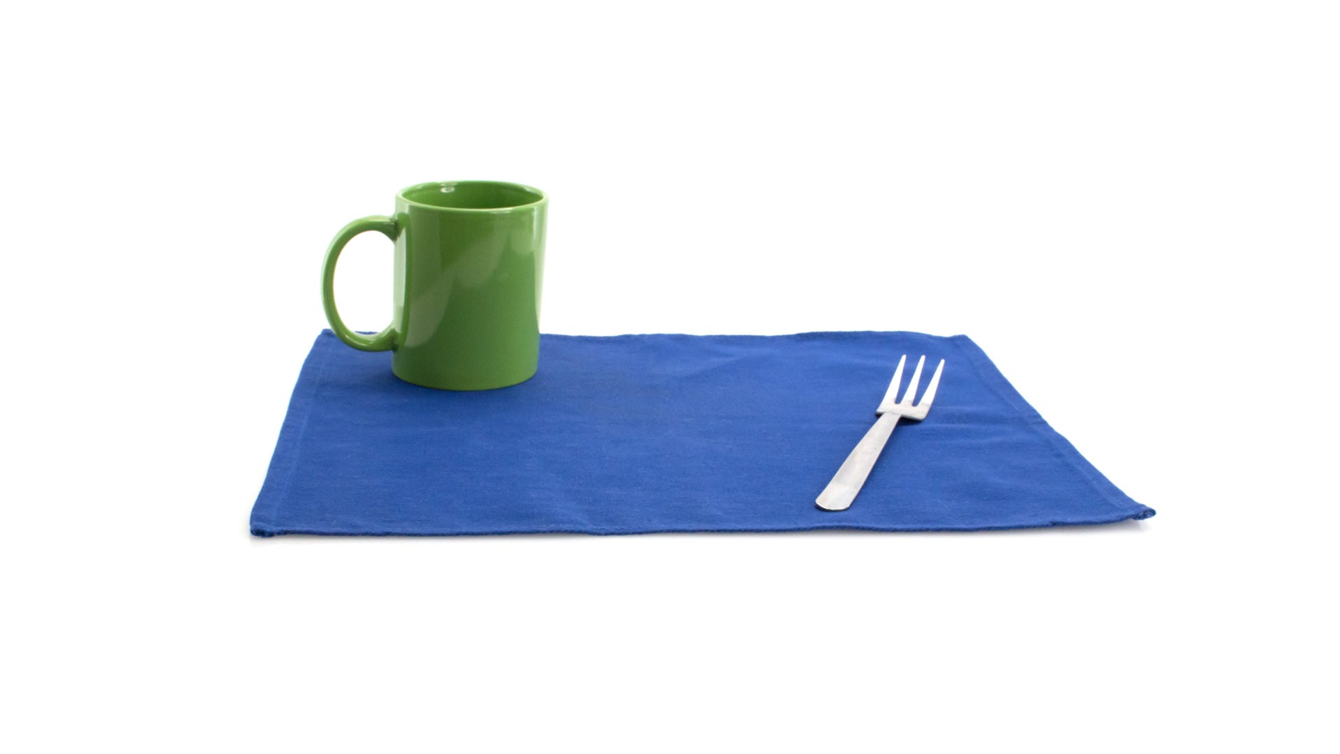 Set de table bleu personnalisable 100% coton déplié, avec une tasse verte et une fourchette à 3 branches posées dessus.